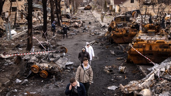 La gente cammina in mezzo ai detriti e veicoli militari russi distrutti in una strada a Bucha, in Ucraina, il 6 aprile 2022.